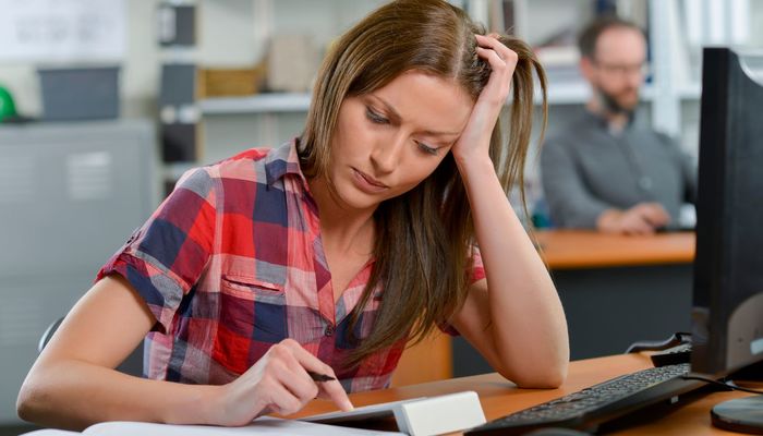 Female employee looking sad and frustrated while working at her desk