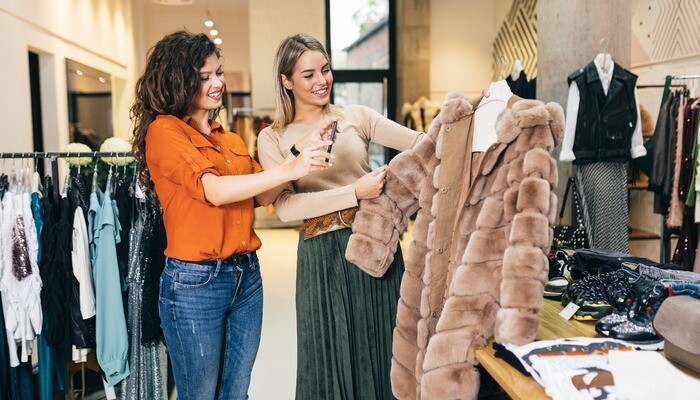 Retail boutique owner looking at a fur coat with a customer