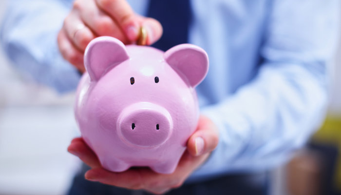 Businessman putting coin into piggy bank