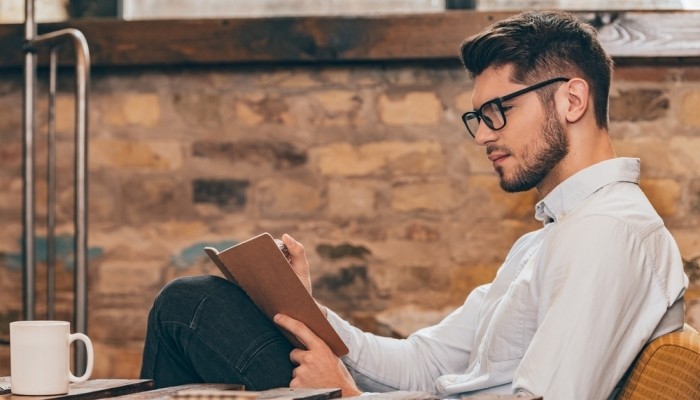 Handsome Young Man In Glasses Writing In His Note Pad