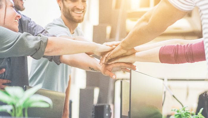 Close-up of a diverse group of young people stacking hands in an office